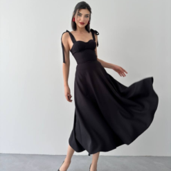 فستان أسود يتميز بحمالات كتف يمكن ربطها على شكل عقد